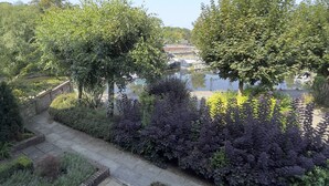 Un jardin où l’on trouve une grande variété de plantes, avec un sentier qui mène à un point d’eau.