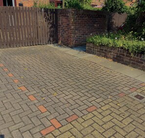 A paved outdoor area with a brick wall and a wooden fence.