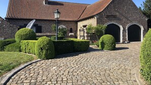 A historic building with a tiled roof, brick walls, and a cobblestone courtyard. - 14P 5B Villa de Poothoeve with Sauna and beautiful garden (Bilzen)