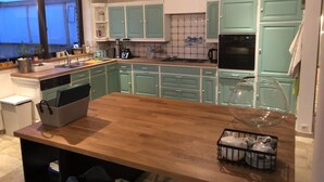 A modern kitchen with teal cabinets, a wooden countertop, and a glass-enclosed island. - 14P 5B Villa de Poothoeve with Sauna and beautiful garden (Bilzen)