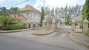A gated residential area with houses, a fountain, and a well-maintained lawn.
