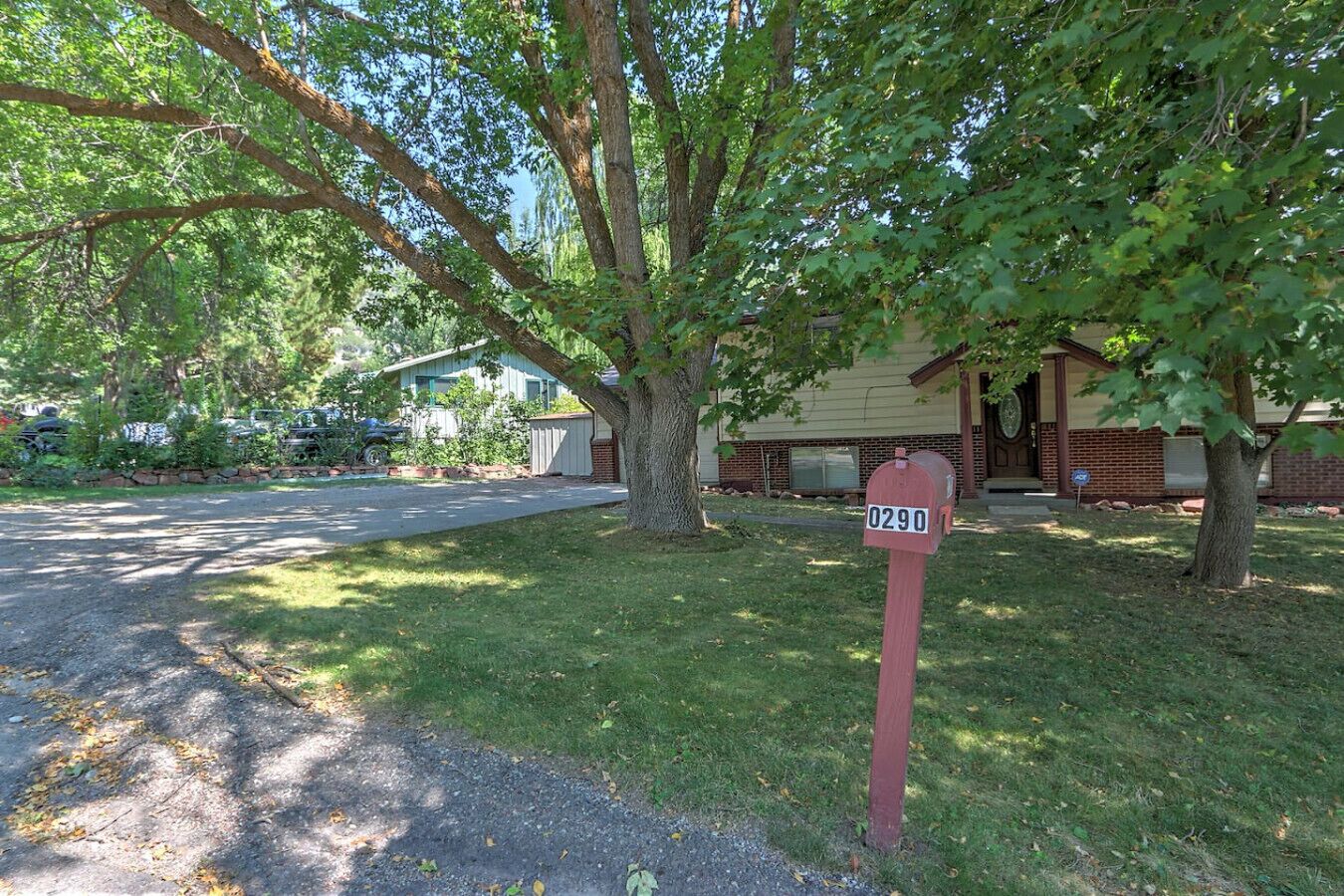 A residential area with a mailbox labeled 0290, a house with a brick facade, and a driveway leading to the house.