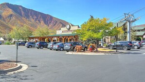 Un estacionamiento con coches, un edificio con un reloj y montañas al fondo.