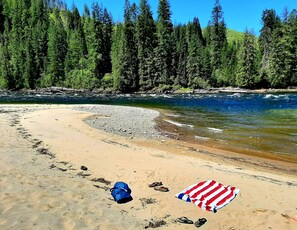 A beach with a clear river, a sandy shore, and a forest in the background. - Rivers Bend Cabin<br>Across from Clearwater <br>river  (Kamiah)