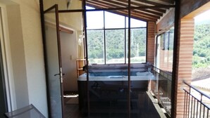 Eine Holterrasse mit einer Glastür zum Bereich eines Whirlpools.