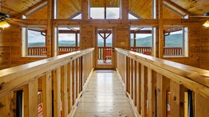A wooden interior with a central staircase leading to a balcony with a view of mountains. - New Construction Mountain Views, Hot Tub and Theater (Pigeon Forge)