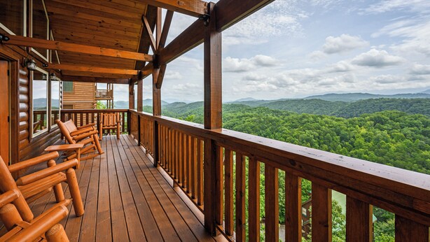 A wooden deck with built-in seating and a view of a forested mountain range. - New Construction Mountain Views, Hot Tub and Theater (Pigeon Forge)