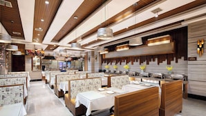 Un restaurante moderno con paneles de madera, manteles blancos e iluminación colgante.