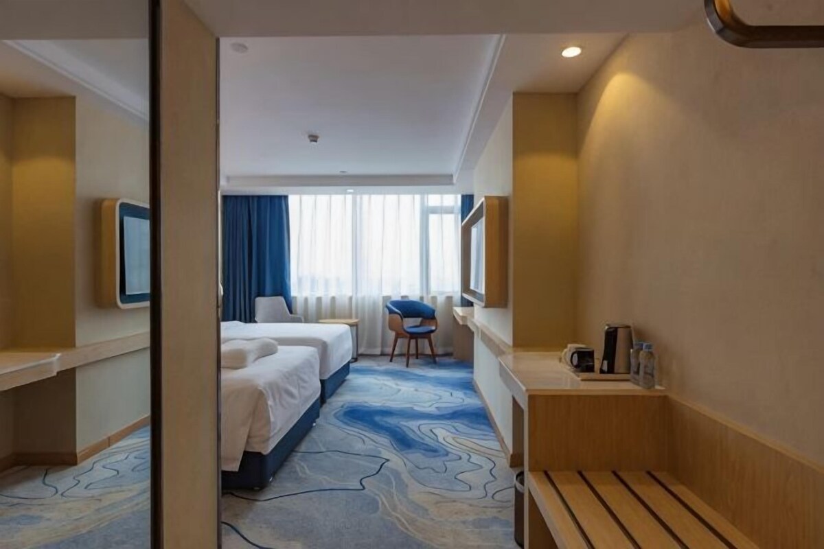 A hotel room with a bed, a desk, a chair, and a television.