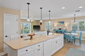 A kitchen with a large island, white cabinets, and pendant lighting.