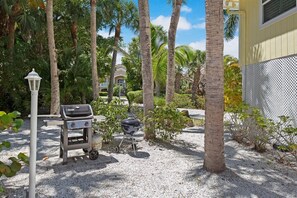 A patio area with a grill, a street lamp, and palm trees. - Welcome to "Little Sanibel" 2/2 with Pool on East End Sanibel (Sanibel)