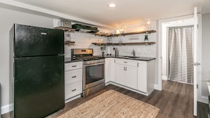Una cocina moderna con armarios blancos, un refrigerador negro, horno empotrado y estufa de acero inoxidable.