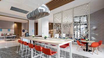 A modern hotel lobby with a central bar area, seating arrangements, and decorative elements.