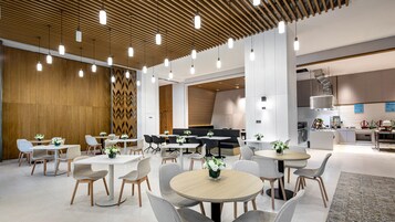 Un área de comedor moderna con mesas redondas, sillas grises y centros de mesa con flores blancas.