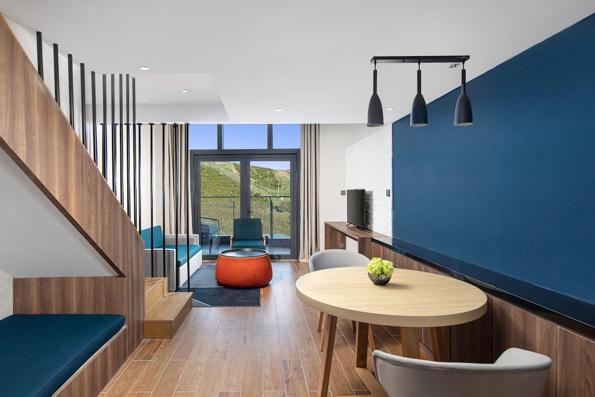 Un interior moderno con una escalera, un comedor y vistas al exterior.