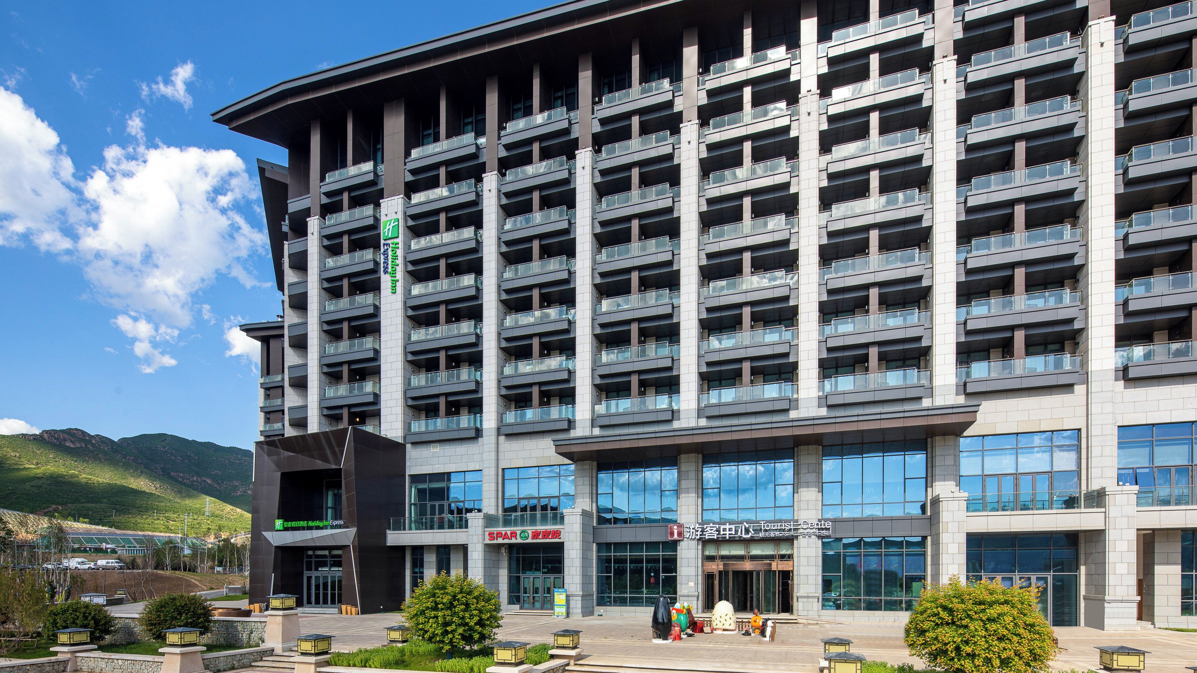 A modern hotel building with multiple balconies, a tourist center, and a sign for Holiday Inn Express.