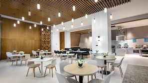 A modern dining area with round tables, grey chairs, and white flower centerpieces. - Holiday Inn Express Chongli (Zhangjiakou)