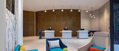 A modern lobby with reception desks, seating areas, and pendant lighting.