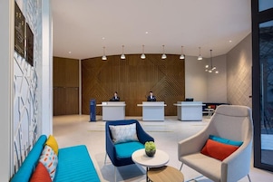 Un lobby moderno con mostradores de recepción, zonas de estar e iluminación colgante.
