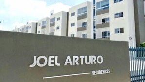 Señal de Joel Arturo Residences con un edificio moderno al fondo.