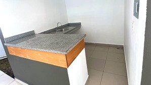 Una cocina compacta con encimera de granito, un lavamanos y un ventanal pequeño.