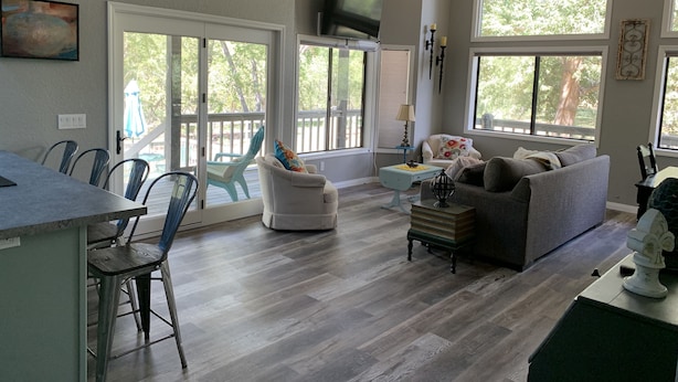 A spacious living area with a dining table, chairs, a sofa, and a television. - Creekside Cabin Under the Sycamores (Lake Montezuma)