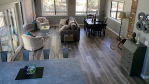 A spacious living area with a dining table, sofas, and a kitchen area with a brick accent wall. - Creekside Cabin Under the Sycamores (Lake Montezuma)