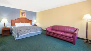 A hotel room with a bed, a purple sofa, two bedside lamps, and a framed picture on the wall. - Blue Way Inn Suites Wichita East (Wichita)
