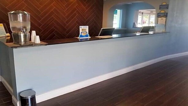 A reception area with a wooden herringbone wall, a reception desk, a coffee machine, and a sign indicating a 'Best' award. - Blue Way Inn Suites Wichita East (Wichita)