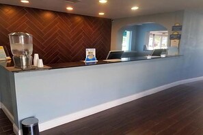 A reception area with a wooden herringbone wall, a reception desk, a coffee machine, and a sign indicating a 'Best' award. - Blue Way Inn Suites Wichita East (Wichita)