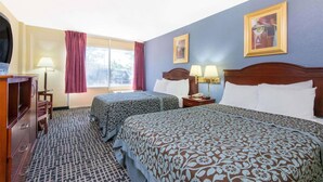 A hotel room with two beds, a desk, a chair, a TV, and a window with curtains. - Blue Way Inn Suites Wichita East (Wichita)