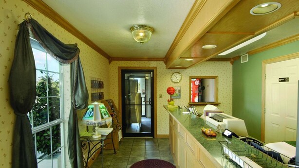 A narrow kitchen with a window, a refrigerator, a sink, and a counter with a coffee machine.