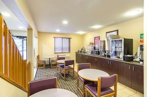 A hotel room with a kitchenette, a dining area with chairs and a table, a window with blinds, and a wooden staircase. - Americas Best Value Inn Fargo (Fargo)