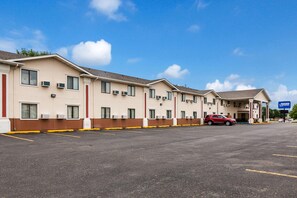 Ein Motel mit Parkplatz, ein rotes Auto auf dem Parkplatz und ein strahlend blauer Himmel.
