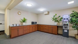 A kitchen with wooden cabinets, a microwave, an ATM, and potted plants. - Americas Best Value Inn Fargo (Fargo)