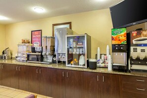 A hotel kitchen with a coffee station, a refrigerator, a microwave, and a coffee machine.