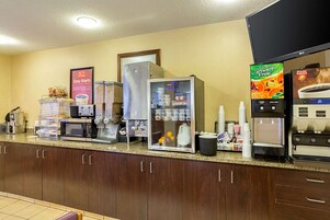 Una cocina de hotel con estación de café, refrigerador, microondas y máquina de café.