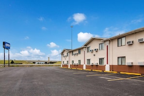 A hotel with a parking lot, multiple air conditioning units, and a clear sky. - Americas Best Value Inn Fargo (Fargo)