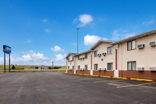 A hotel with a parking lot, multiple air conditioning units, and a clear sky. - Americas Best Value Inn Fargo (Fargo)