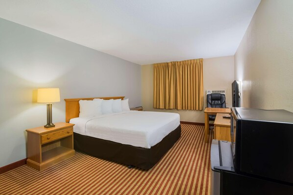 A hotel room with a bed, a desk, a television, and a lamp.