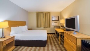 A hotel room with a bed, a desk with a TV, a lamp, a chair, and a dresser. - Americas Best Value Inn Fargo (Fargo)