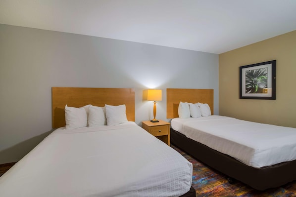 A hotel room with two beds, a nightstand with a lamp, and a framed picture on the wall. - Americas Best Value Inn Fargo (Fargo)