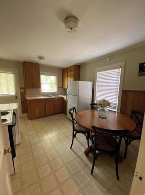 Enjoy meals in this kitchen with a dining table and chairs, a refrigerator, and a window with blinds.