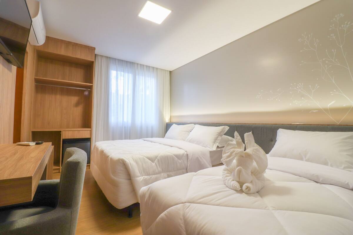A hotel room with two beds, a desk, and a chair.