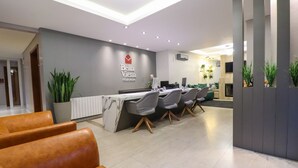 A modern reception area with a marble counter, leather seating, and a logo for Bella Vienna Pousada. - Pousada Bella Viena (Gramado)