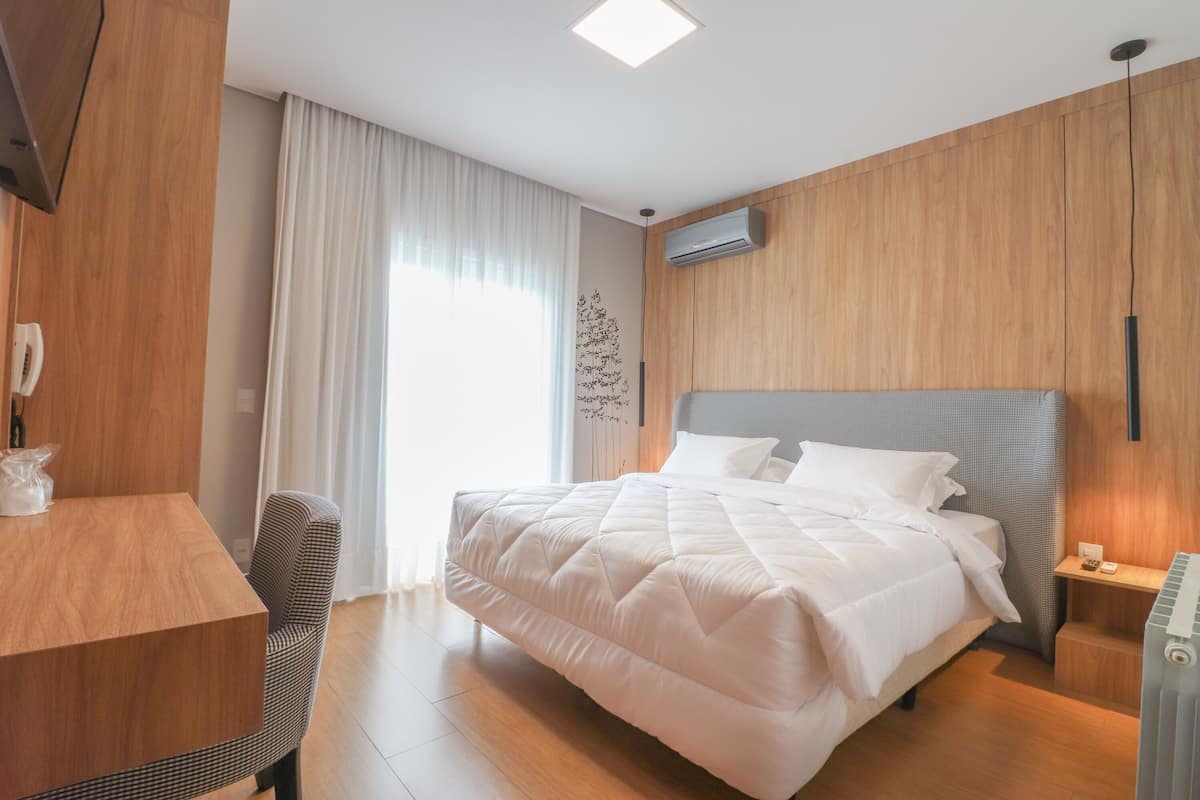 A modern hotel room with a large bed, a wooden desk, and a chair.