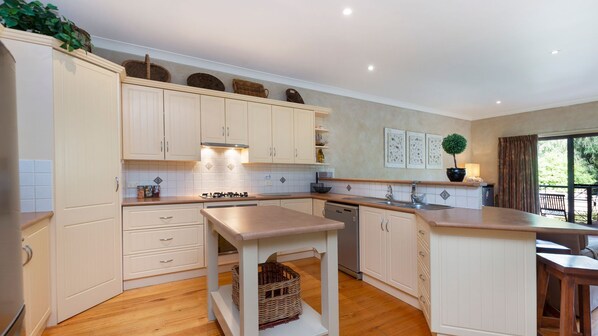 A modern kitchen with white cabinetry, a central island, and a view of the outdoors. - Mediterranean styled house around the corner form East Beach (Port Fairy)