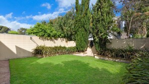 Enjoy a serene outdoor space with a beautifully manicured lawn, shrubs, and a tall tree.