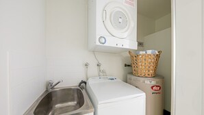 Een kleine wasruimte met een wasmachine, een droger en een wasbak.