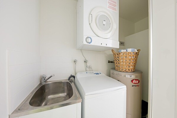 Un lavadero pequeño con lavadora, secadora y lavabo.